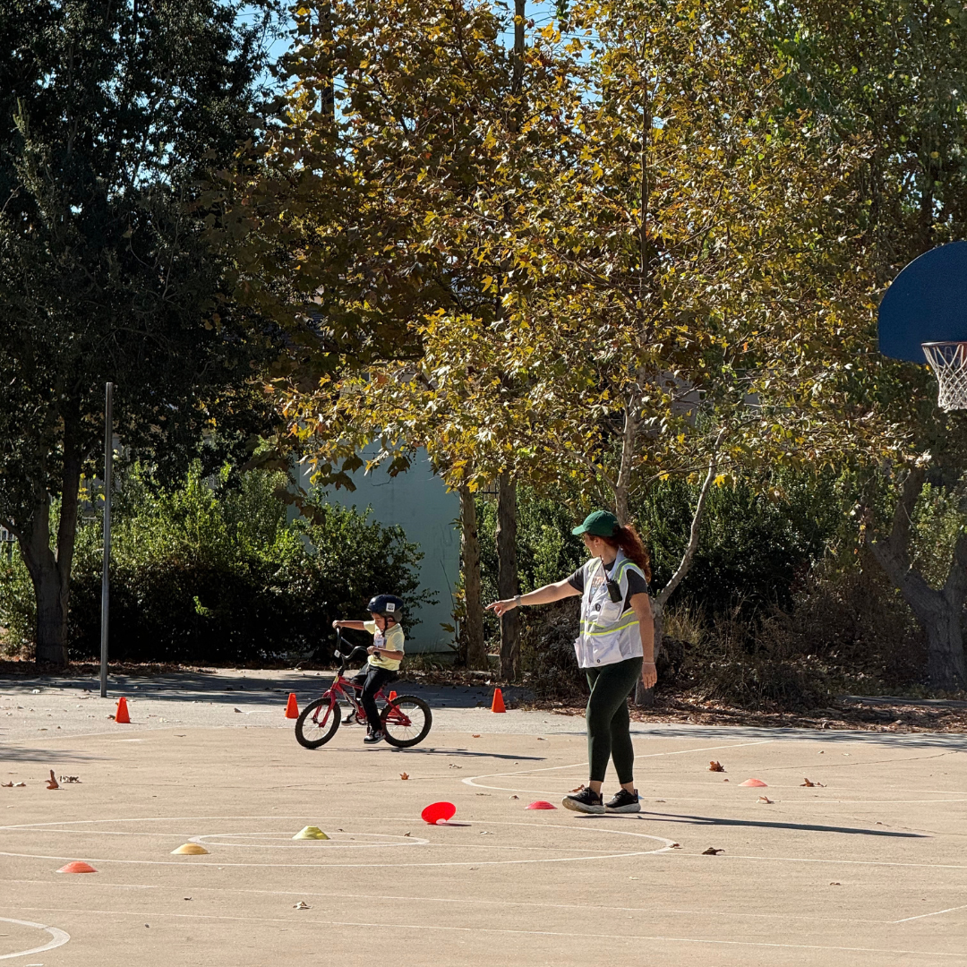 A child on a bike being directed through cones