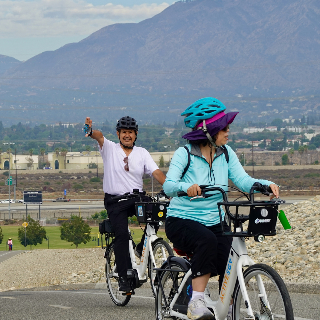 Two cyclists biking up a hill.