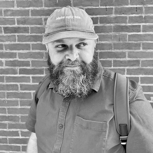 Barry Hott wearing a "Make ugly ads" hat in front of a brick wall