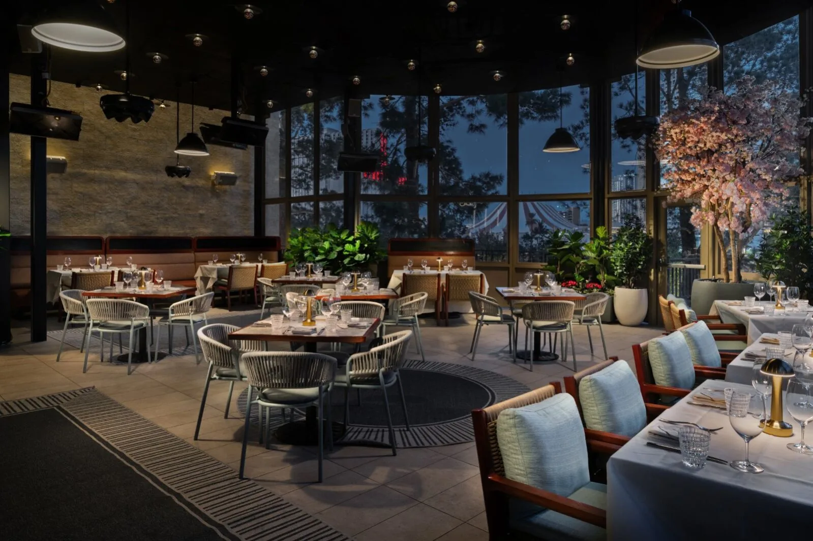 Carversteak patio dining area with tables, banquettes, plants, and windscreen walls looking out at night