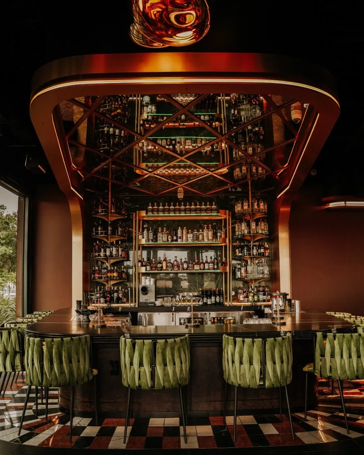 Rare Society bar with copper canopy, back bar display, and green stools