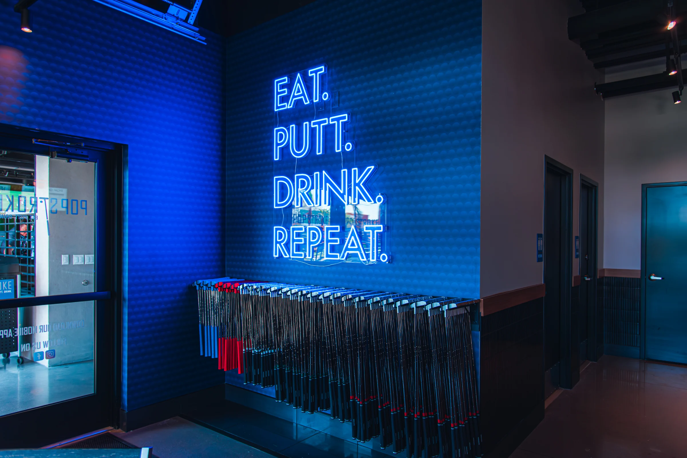 PopStroke interior arrival wall with illuminated Eat Putt Drink Repeat lettering