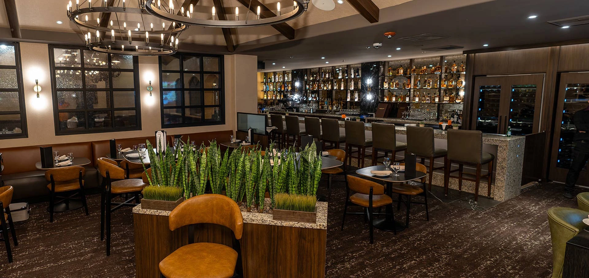Katherine’s Steakhouse lounge and bar at CasaBlanca, with chandeliers, banquette seating and illuminated bottle shelves