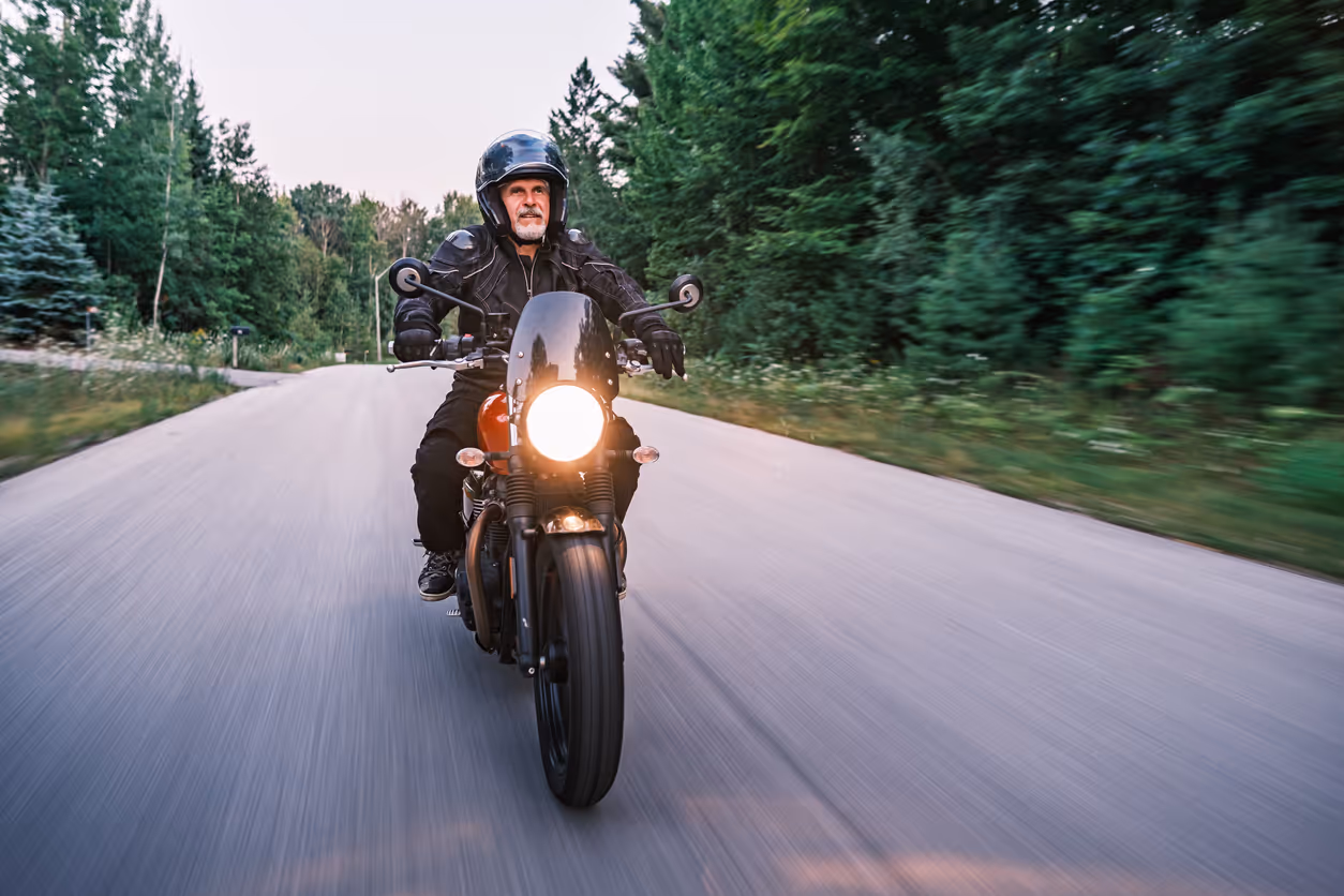 Mature man riding his motorbike in the countryside at dawn