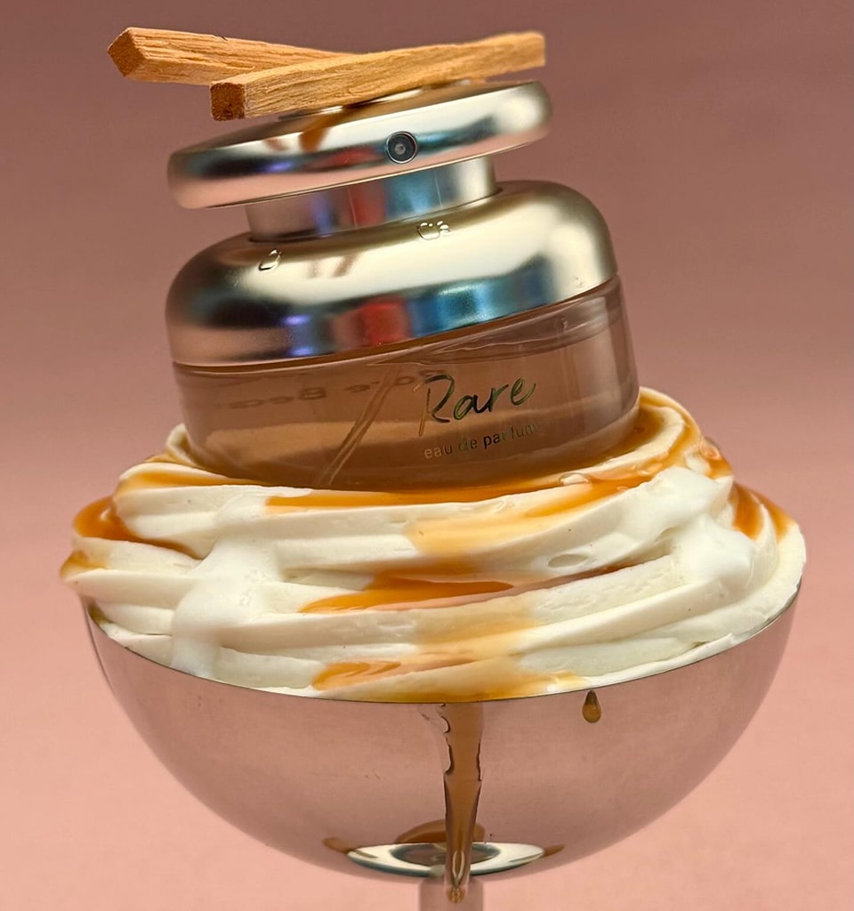 Rare perfume bottle styled on whipped cream with caramel drizzle against pink background