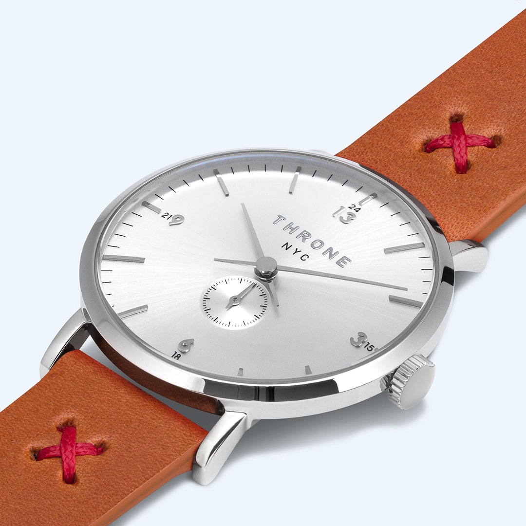 Minimalist silver analog watch with a tan leather strap displayed on a light background.