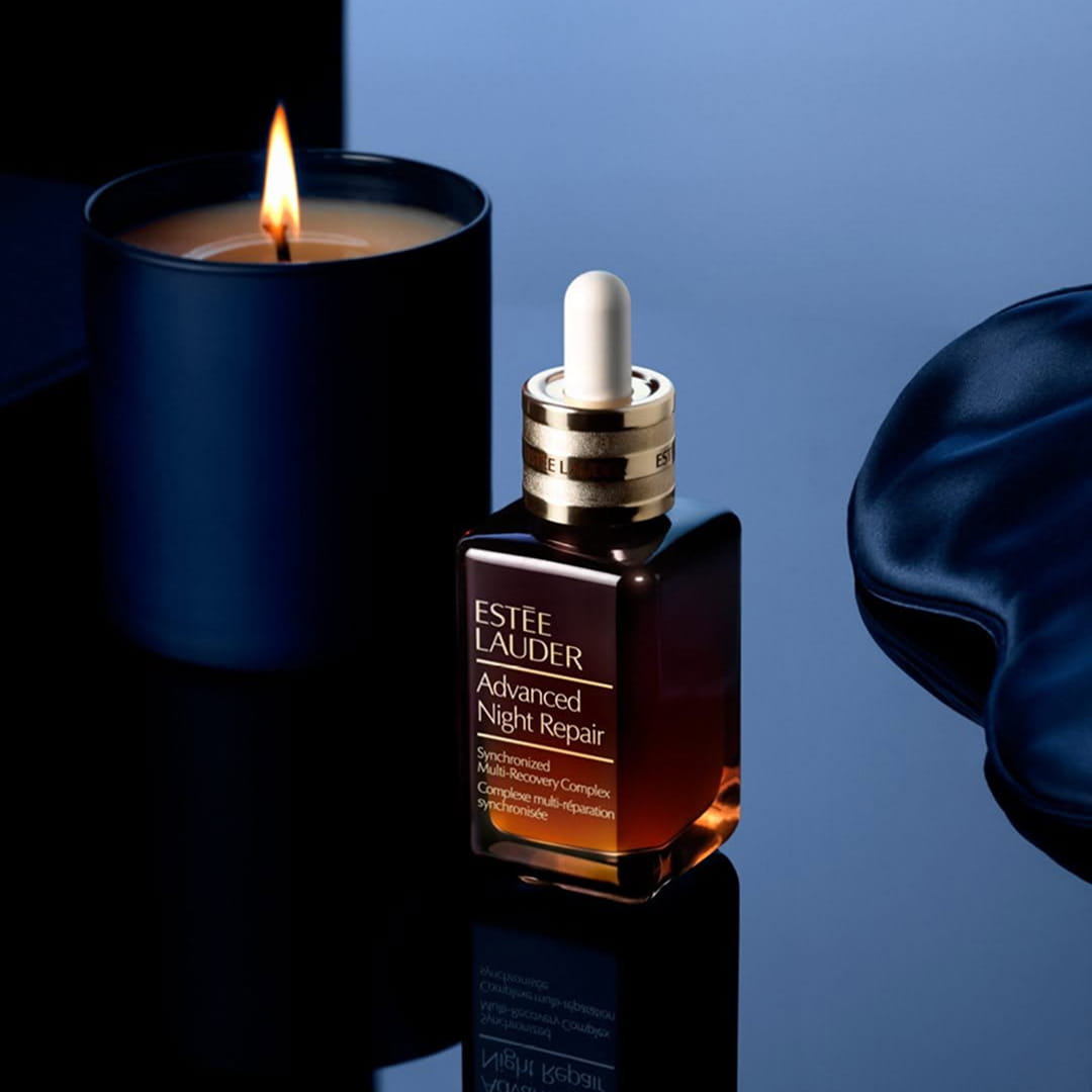 Estée Lauder Advanced Night Repair serum with candle in dark, moody lighting