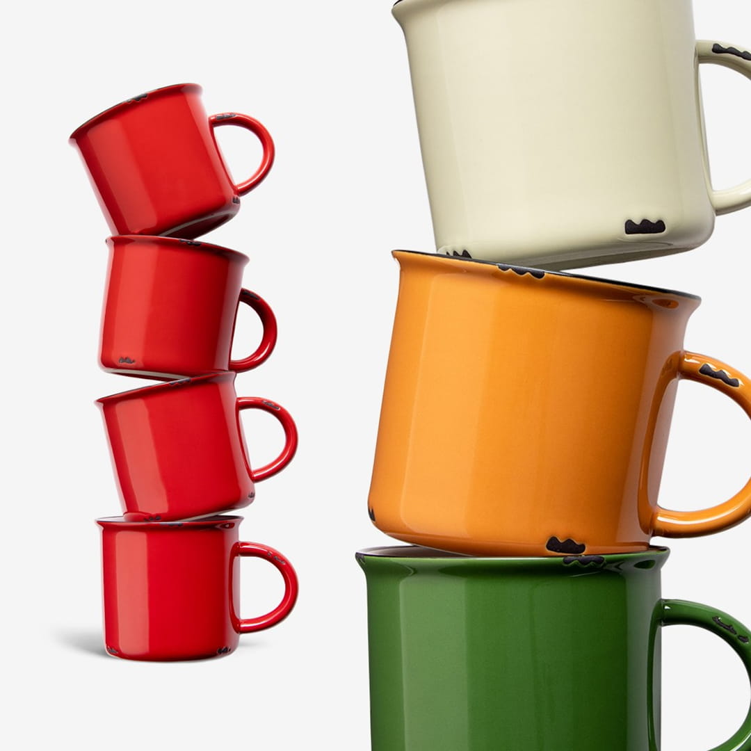 Stacked ceramic mugs in red, cream, orange, and green on a neutral background