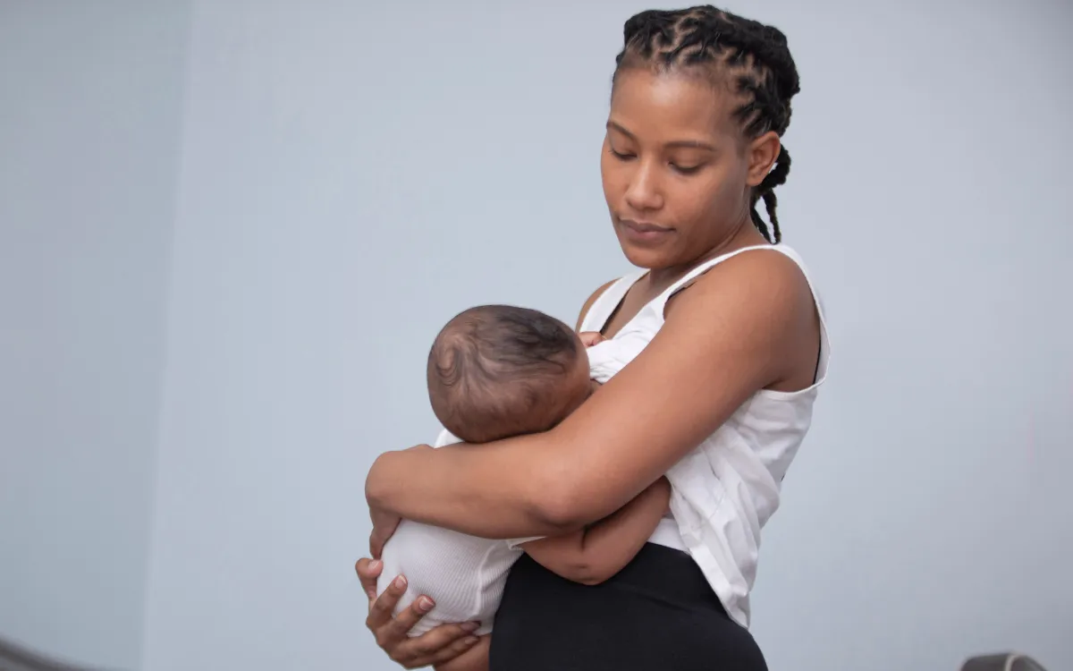 woman standing up and breastfeeding baby watching for signs of baby struggling to latch