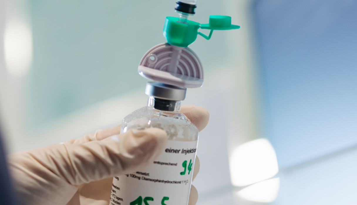 Behandschuhte Hand hält eine Diamorphin-Injektionsflasche