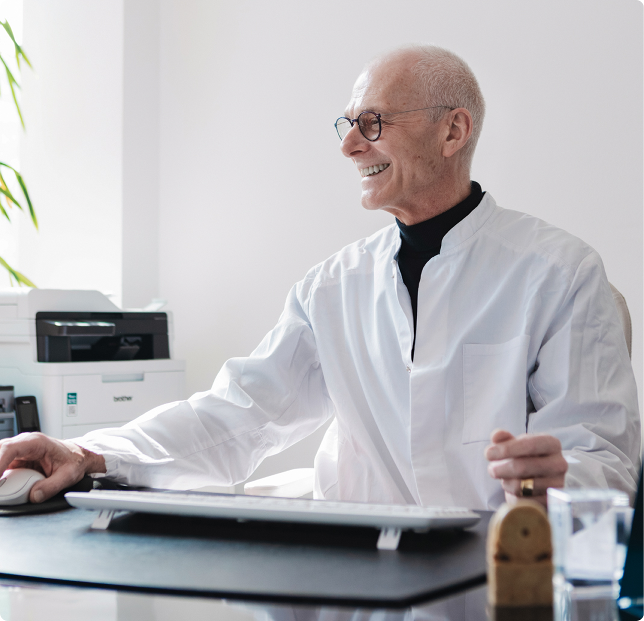 Norbert E. Lyonn am Schreibtisch in der Praxis Lyonn