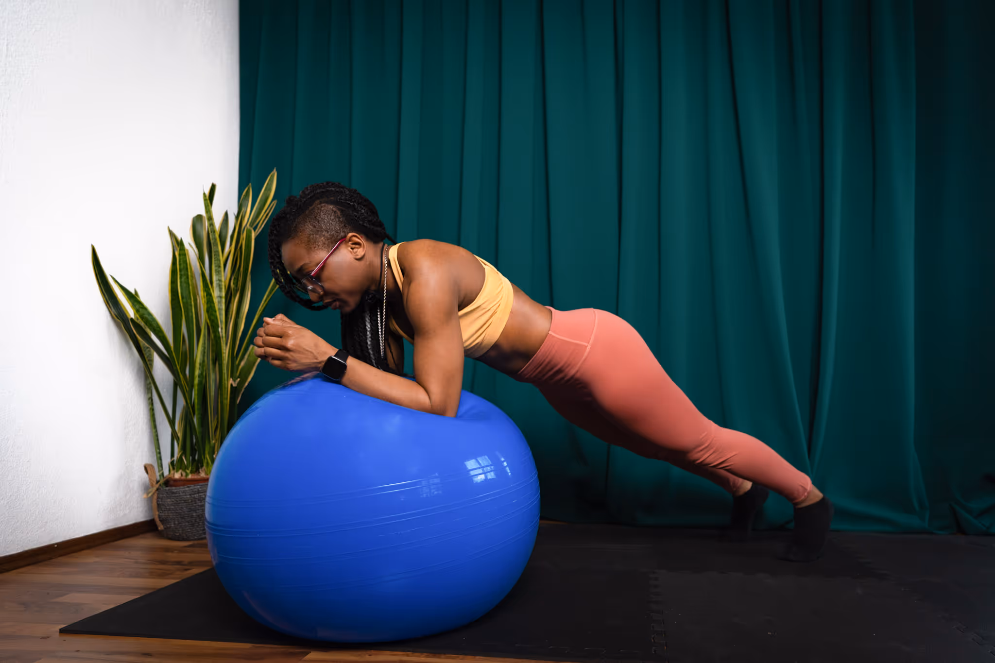 Kerline performing a Lower Arm plank on Gymnastic ball with wisely defined arm and belly muscles.
