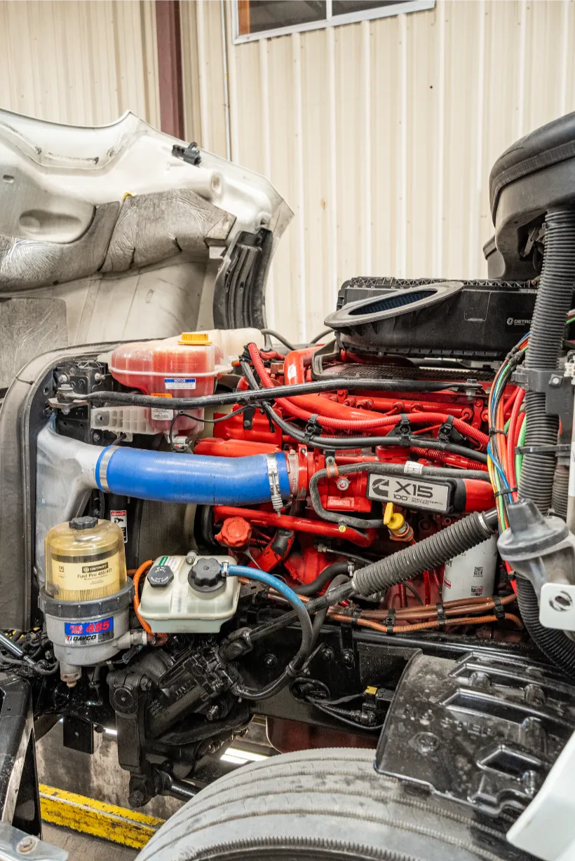 Cummins engine with X15 605 HP badge exposed during heavy-duty truck maintenance inside a service bay.