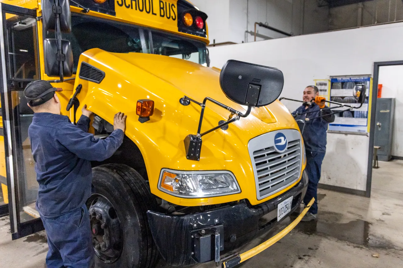 Dashboard warning lights inspection on a school bus during preventive maintenance in a heavy-duty repair shop.