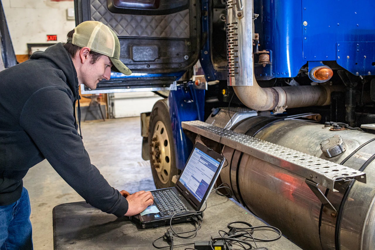 SCR diagnostics on a heavy-duty truck with technician using laptop for emissions system troubleshooting.