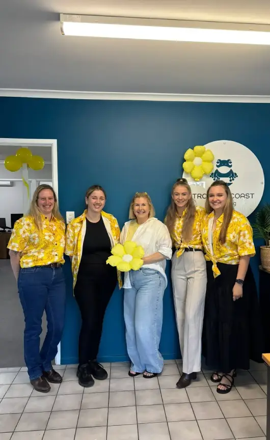 A group of five Tropical Coast Plumbing team members smiling together in the office.
