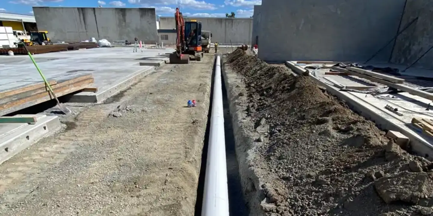 Trench excavation with large commercial drainage pipe installed at an industrial construction site.
