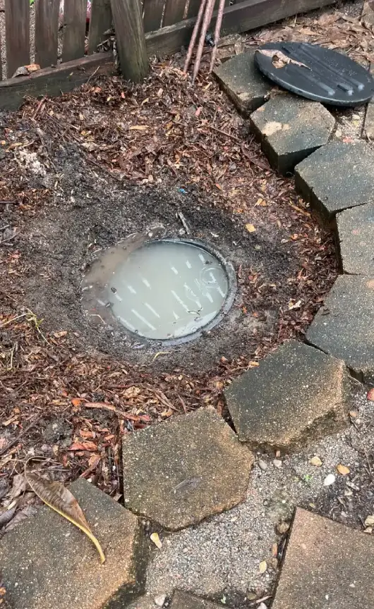 Outdoor grease trap with an open lid showing wastewater buildup, highlighting the need for professional grease trap cleaning and maintenance.
