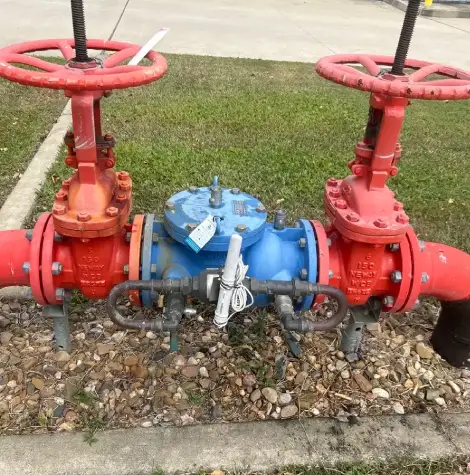 Close-up of a valve assembly with two red gate valves and a blue central unit.
