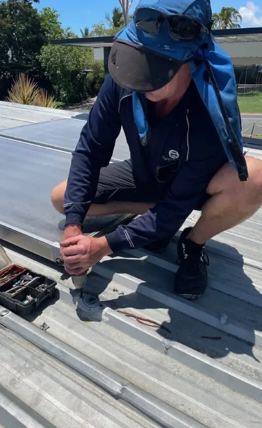 Licensed technician performing maintenance on a metal roof sheet, ensuring secure fixtures and weatherproof sealing, delivering quality workmanship.