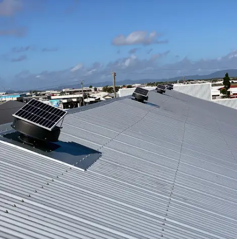 A row of professionally installed Solar King fans mounted on a large commercial metal roof, designed to improve ventilation and reduce indoor temperatures naturally.