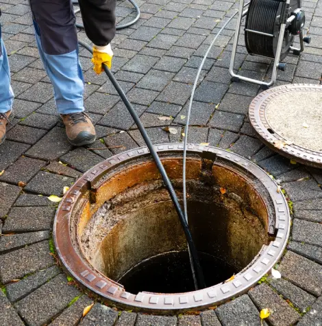 Plumber using drain inspection camera to assess underground pipe condition.
