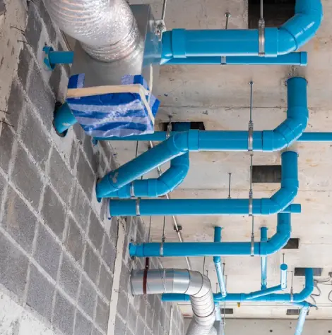 Commercial plumbers preparing a Y-branch pipe liner for a trenchless relining project in a warehouse setting.