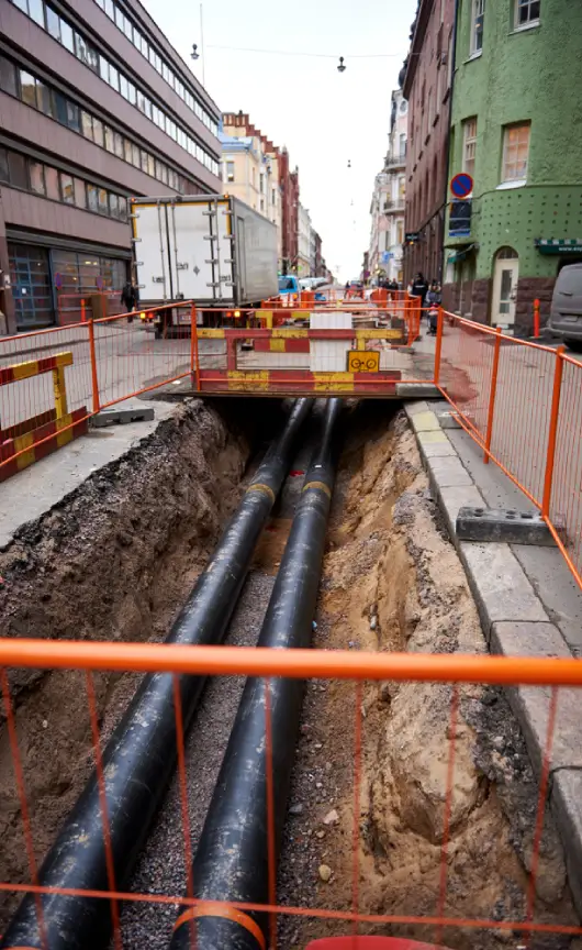 A plumber working on exposed copper and polyethylene pipes during an underground pipe repair.