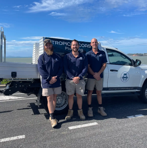 Tropical Coast Plumbing team standing beside service ute overlooking the coast in Yeppoon, ready for pipe repairs and relining jobs.