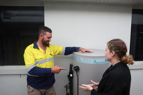 A professional plumber discussing a hot water system with a homeowner.