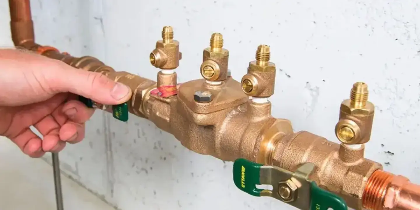 Licensed plumber testing a backflow prevention device valve in Townsville to ensure compliance and protect the clean water supply.