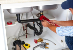 Plumber in Townsville performing pipe repairs under a kitchen sink, fixing leaks quickly to restore water flow and prevent damage.