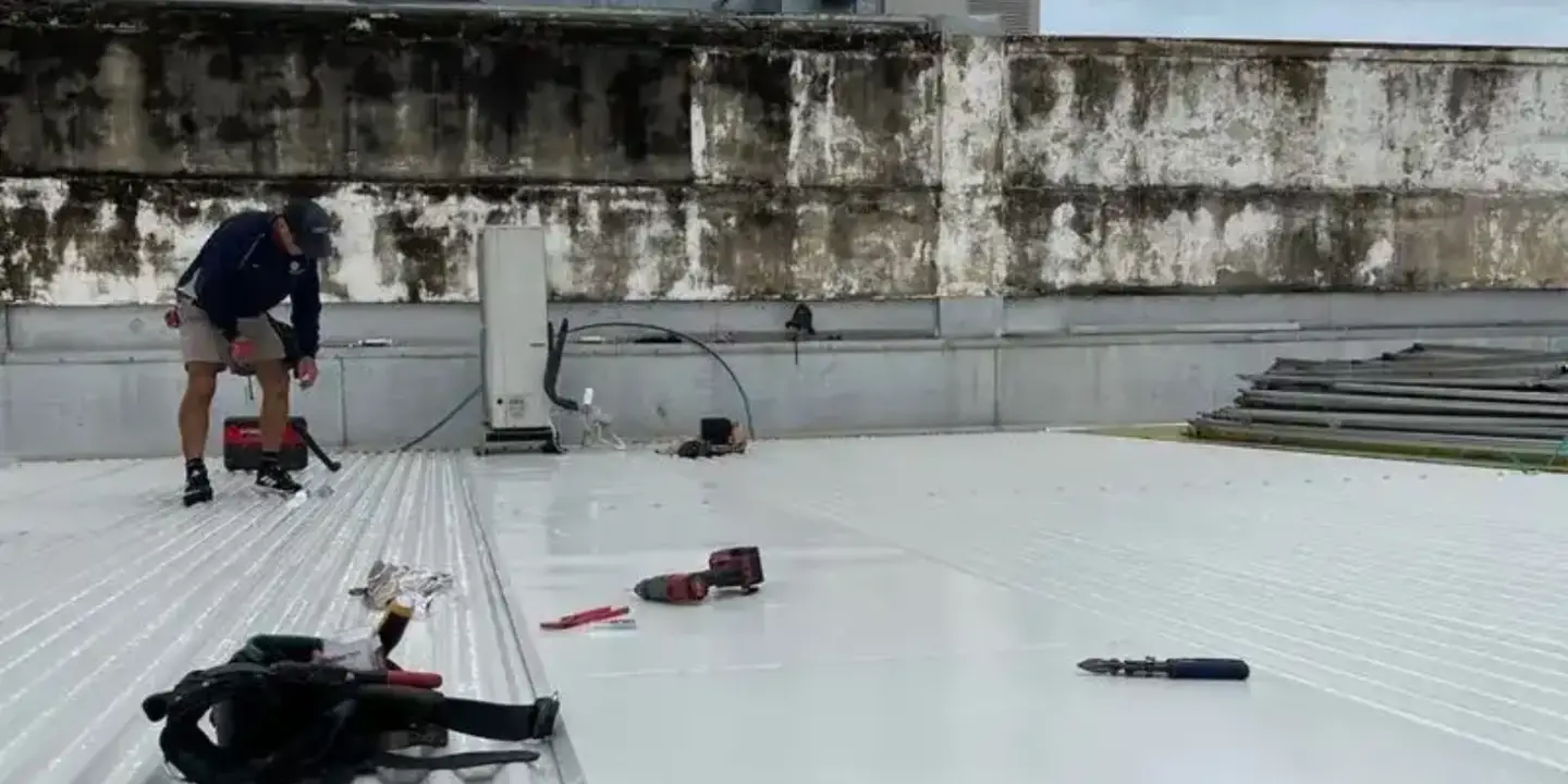 Roof plumber in Townsville carrying out metal roof repairs on a commercial property, ensuring durable and professional roofing services.