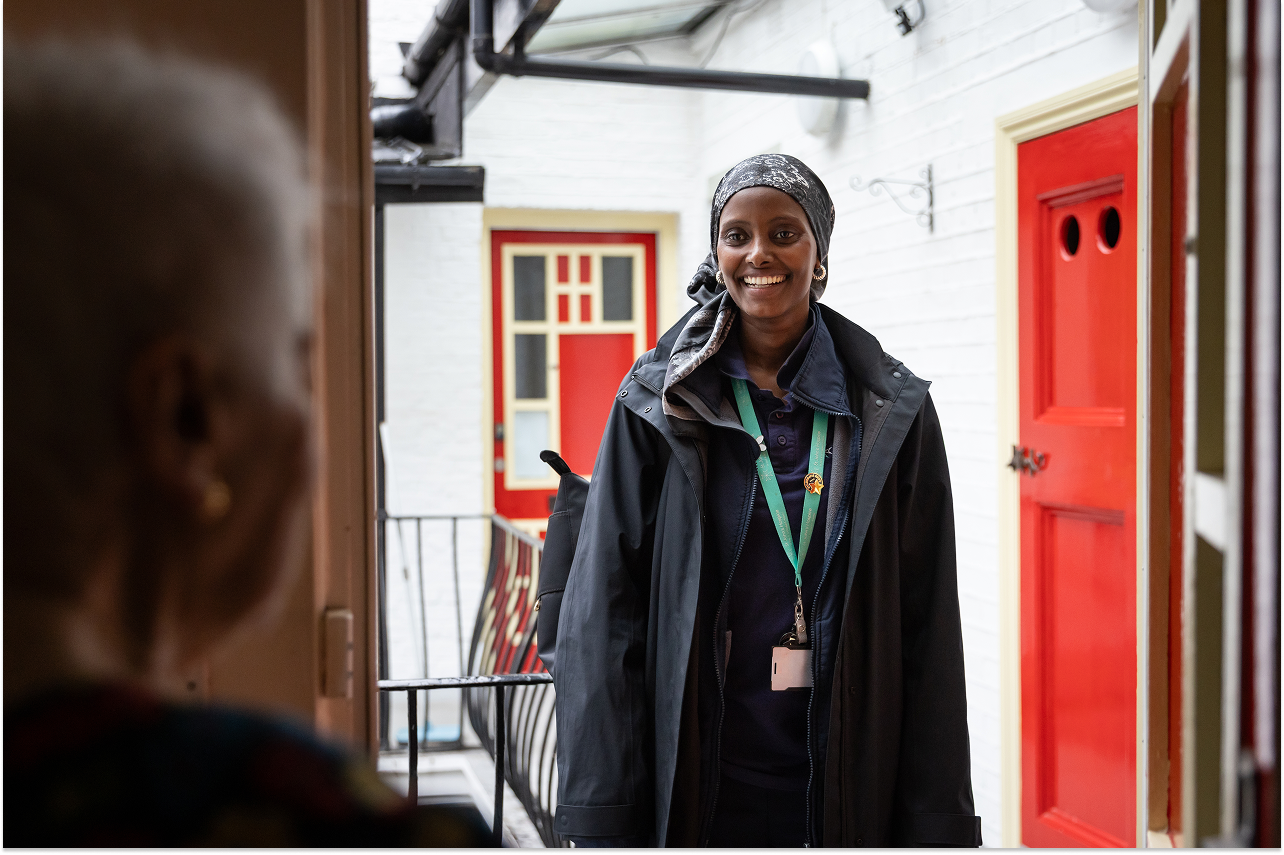 A patient opens the door to her Hospice@Home Healthcare Assistant.