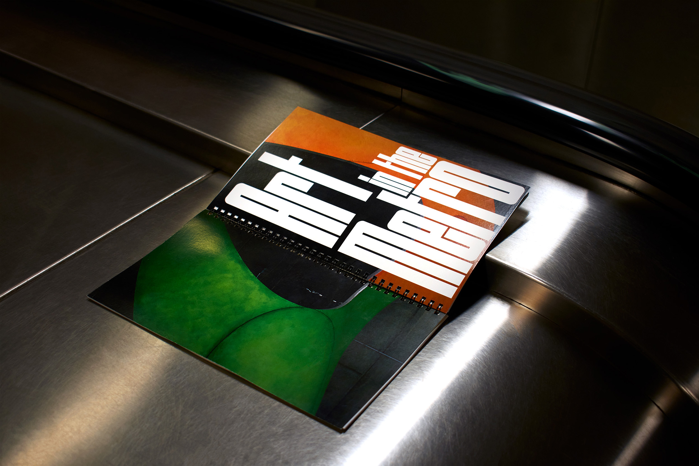 Book design opened and laid down flat on the side of a metro escalator (to show the back and front cover of the book). The image is high contrast to mimic the spots of bright lighting in the metro vs the dark corners of the metro.