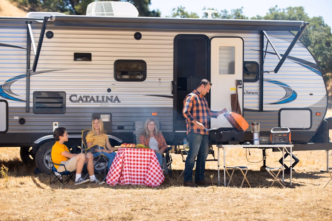 A family enjoying a campsite with their travel trailer, illustrating the lifestyle RV insurance protects - Instant RV insurance quote