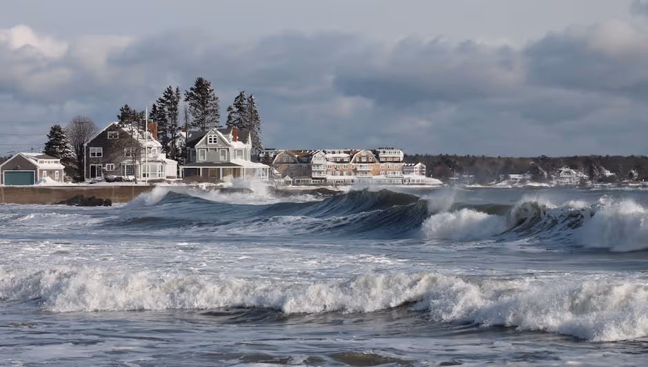 A picturesque coastal home in Maine with a dramatic, stormy sky overhead, emphasizing potential weather risks. - Home insurance Portland