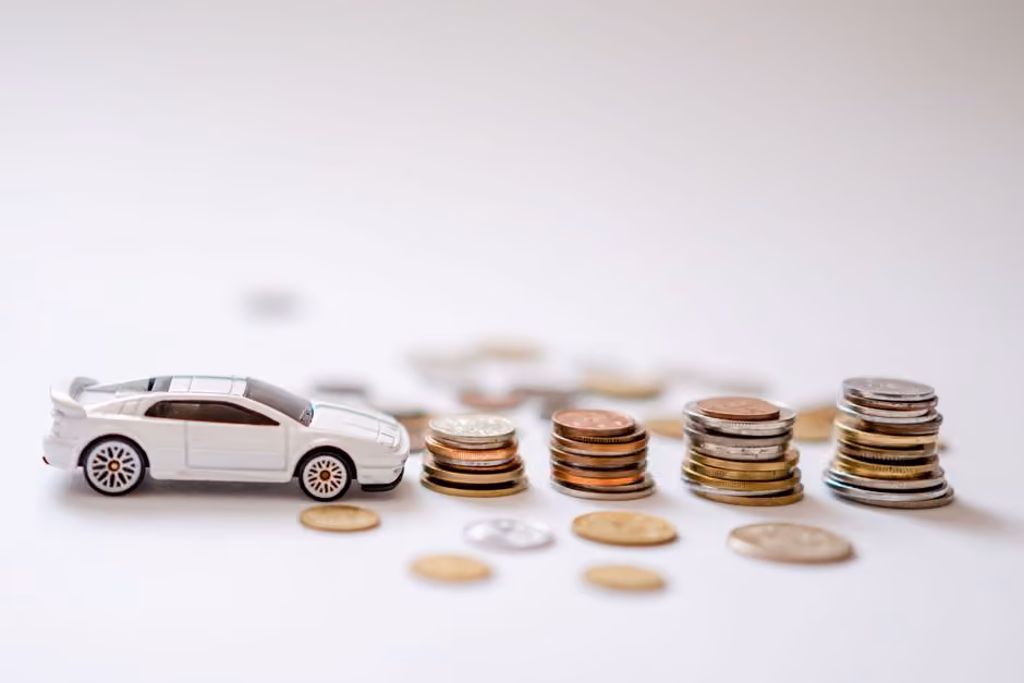 small car in front of stacked coins - auto insurance rates concept