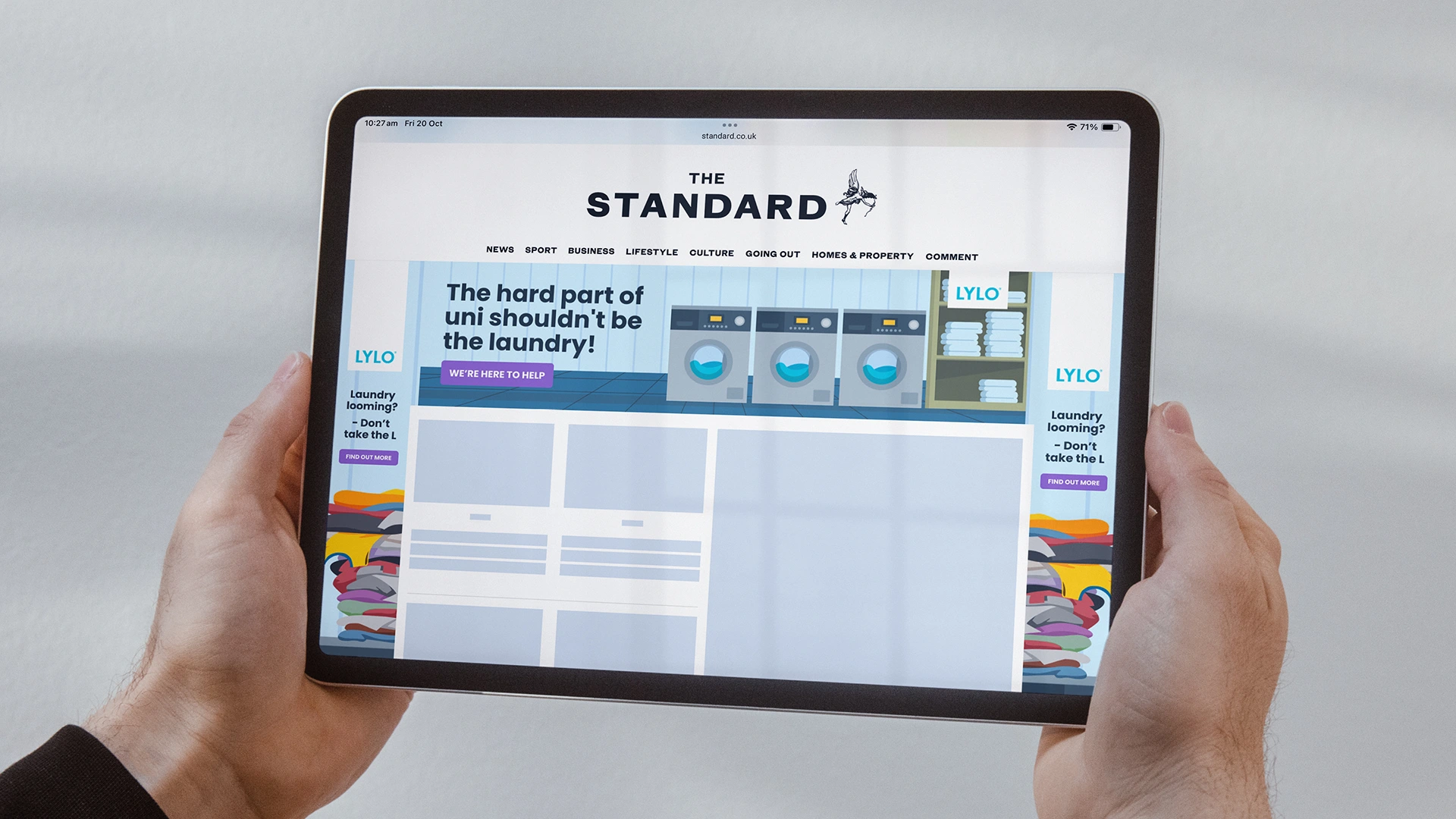 A person holding a tablet showing the Evening Standard website homepage.
