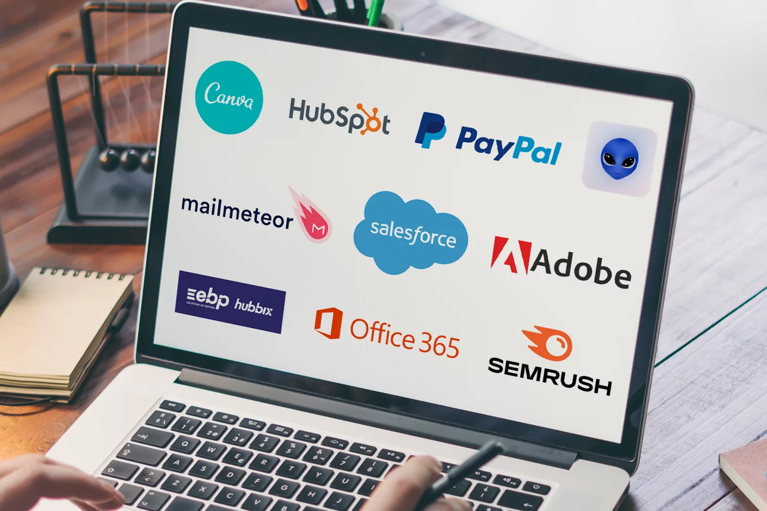 Ordinateur portable affichant les logos de logiciels professionnels comme HubSpot, Salesforce, Adobe et Office 365