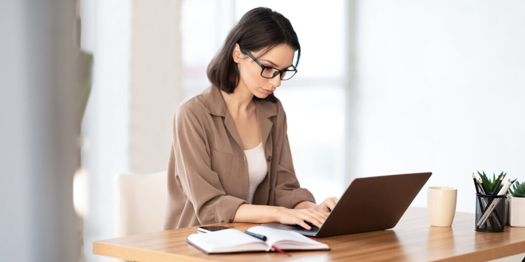 Femme travaillant sur son nouvel ordinateur portable à un bureau en bois