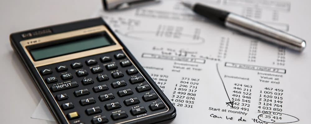 Calculatrice et stylo posés sur des documents financiers