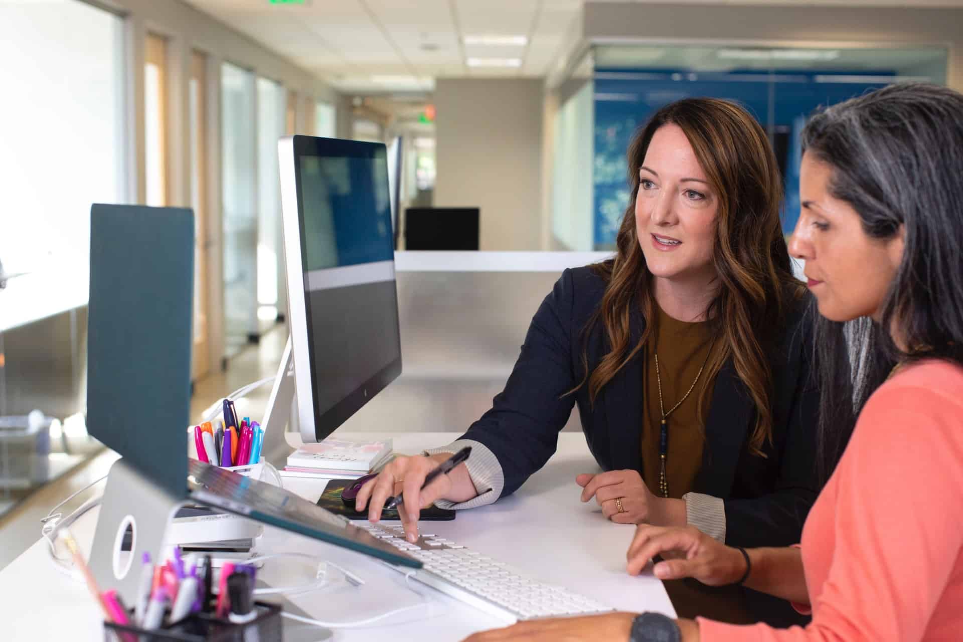 Office manager et collègue travaillant ensemble devant un ordinateur