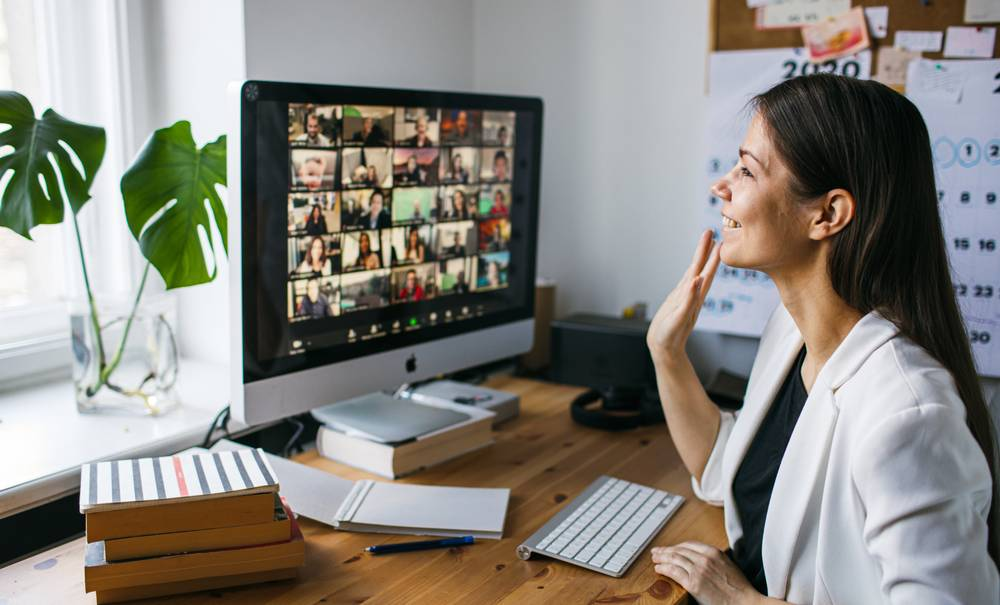 Femme en télétravail participant à une visioconférence sur un iMac