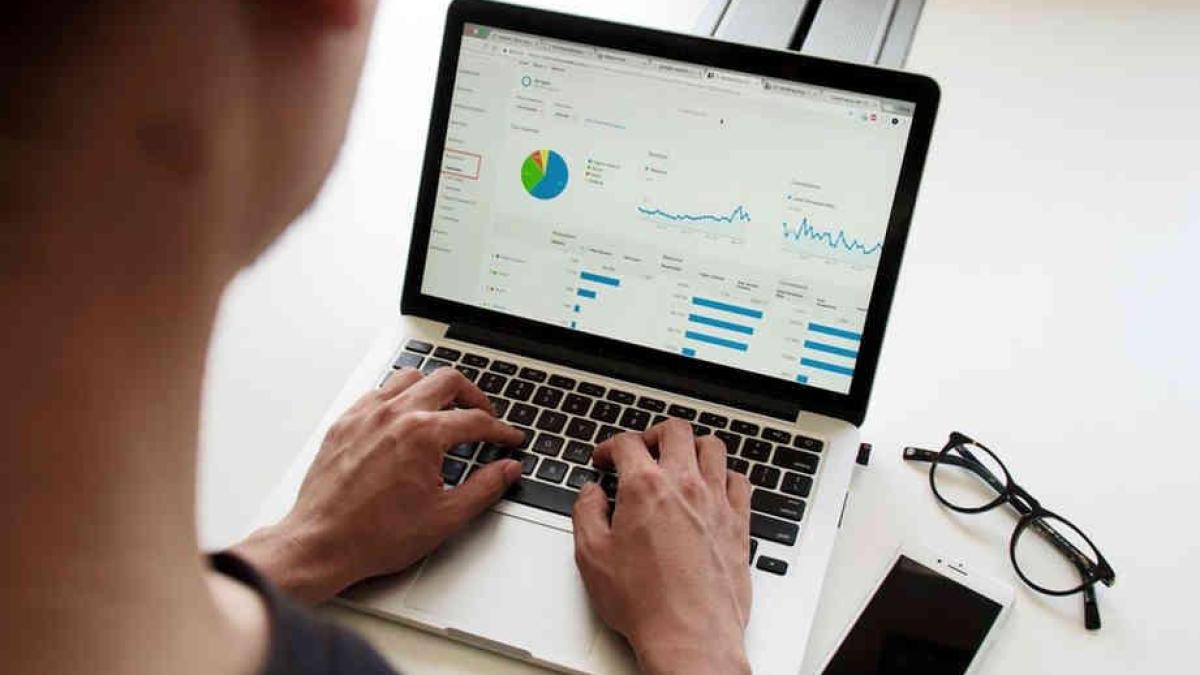 Personne consultant des graphiques sur un ordinateur portable, lunettes posées à côté