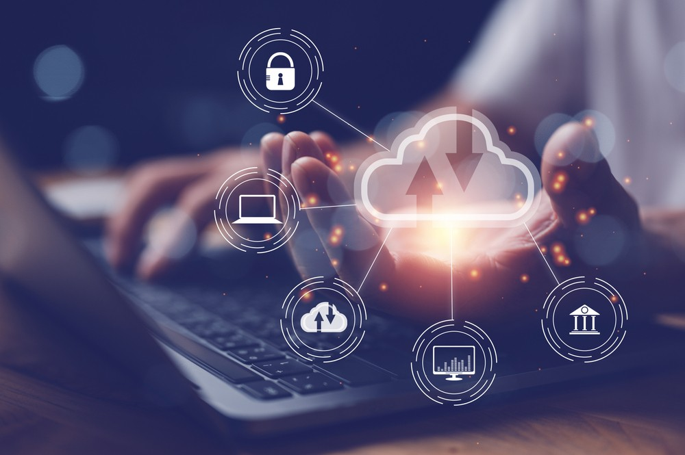 Mains sur un ordinateur portable sous une icône de cloud reliée à des pictogrammes de sécurité