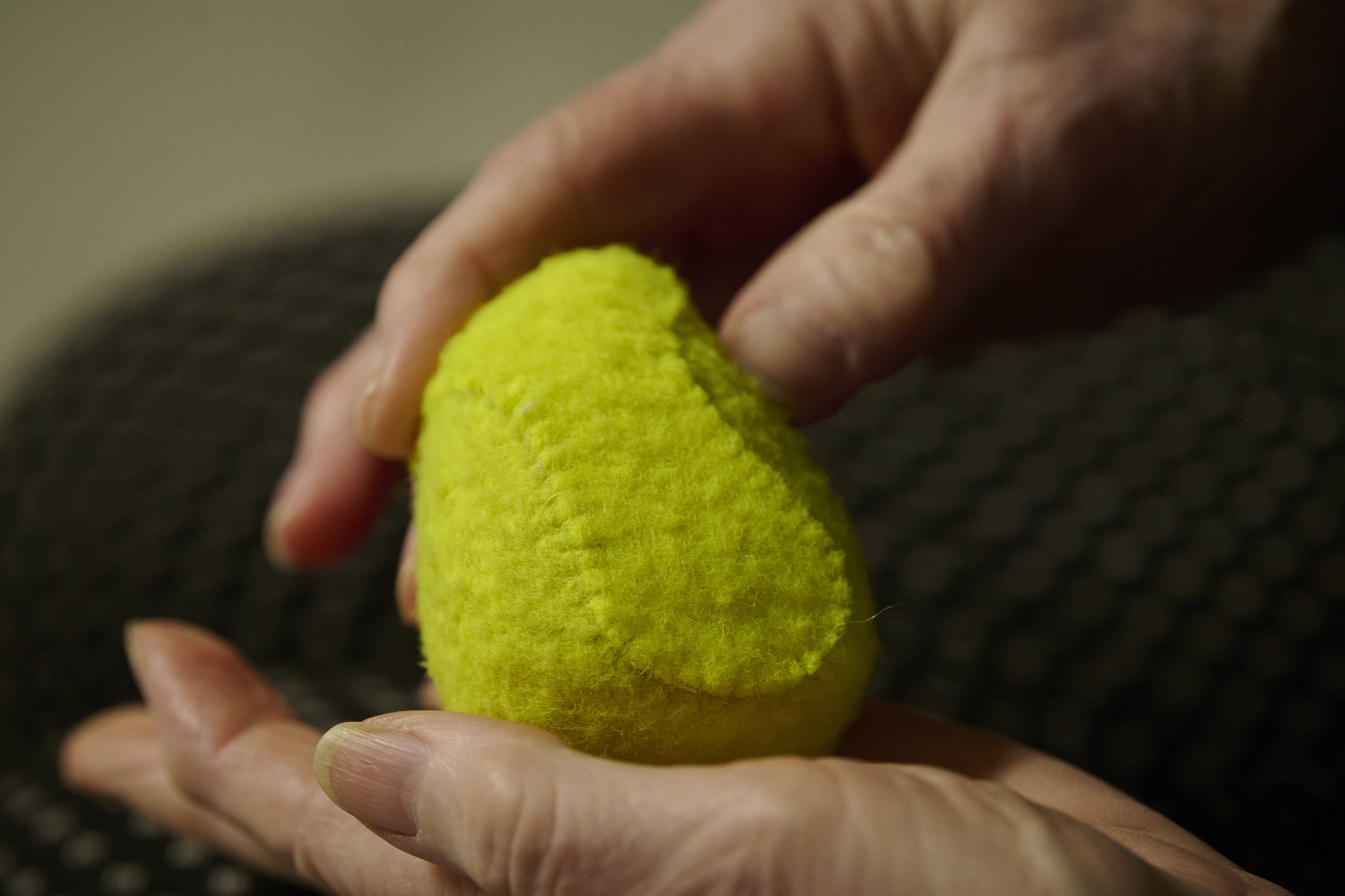 a neon yellow fuzzy object is held between a person's fingers