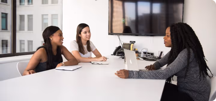 People in a meeting room talking at a desk