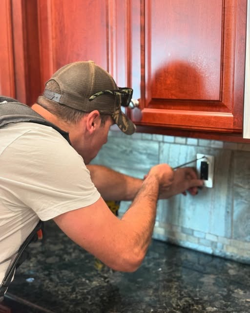 Electrician installing a kitchen outlet under the cabinets