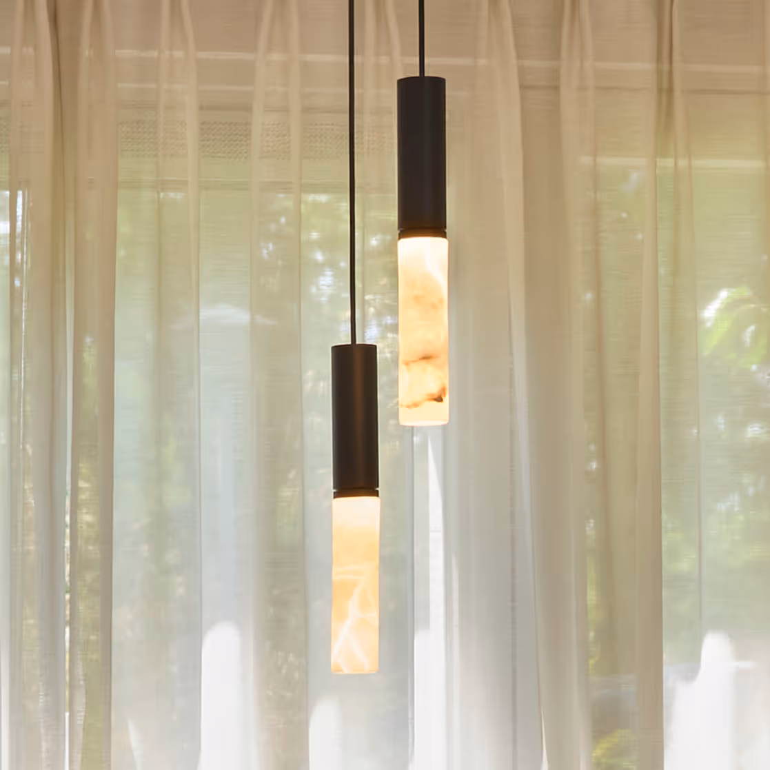 Close-up van twee cilindervormige hanglampen met marmerachtig glas en warm licht.